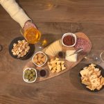 Borrelplank met diverse kazen, salami, olijven, walnoten, crackers en zongedroogde tomatentapenade, geserveerd met een Aperol Spritz