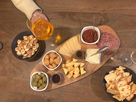 Borrelplank met diverse kazen, salami, olijven, walnoten, crackers en zongedroogde tomatentapenade, geserveerd met een Aperol Spritz