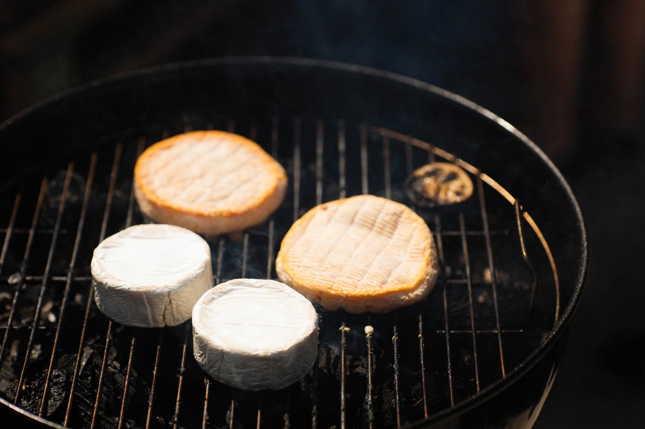 Gesmolten camembert in een gietijzeren pannetje op de barbecue met kruiden
