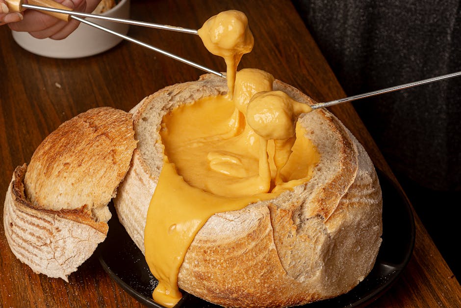 Smeltende kaasfondue met Emmentaler kaas in een rustic broodkom op een houten tafel