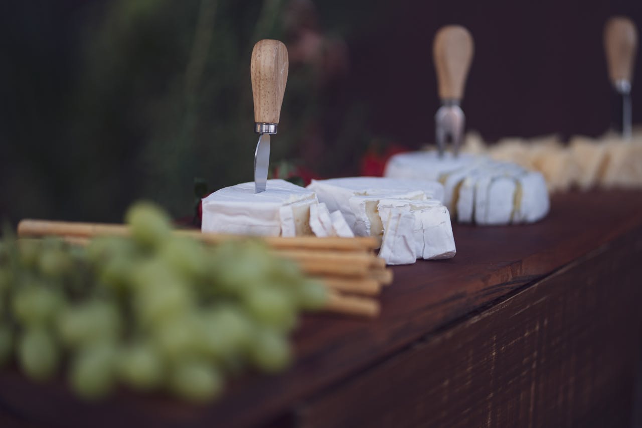 Tabla de quesos con distintos quesos, frutos secos, fruta y crackers sobre una tabla de madera