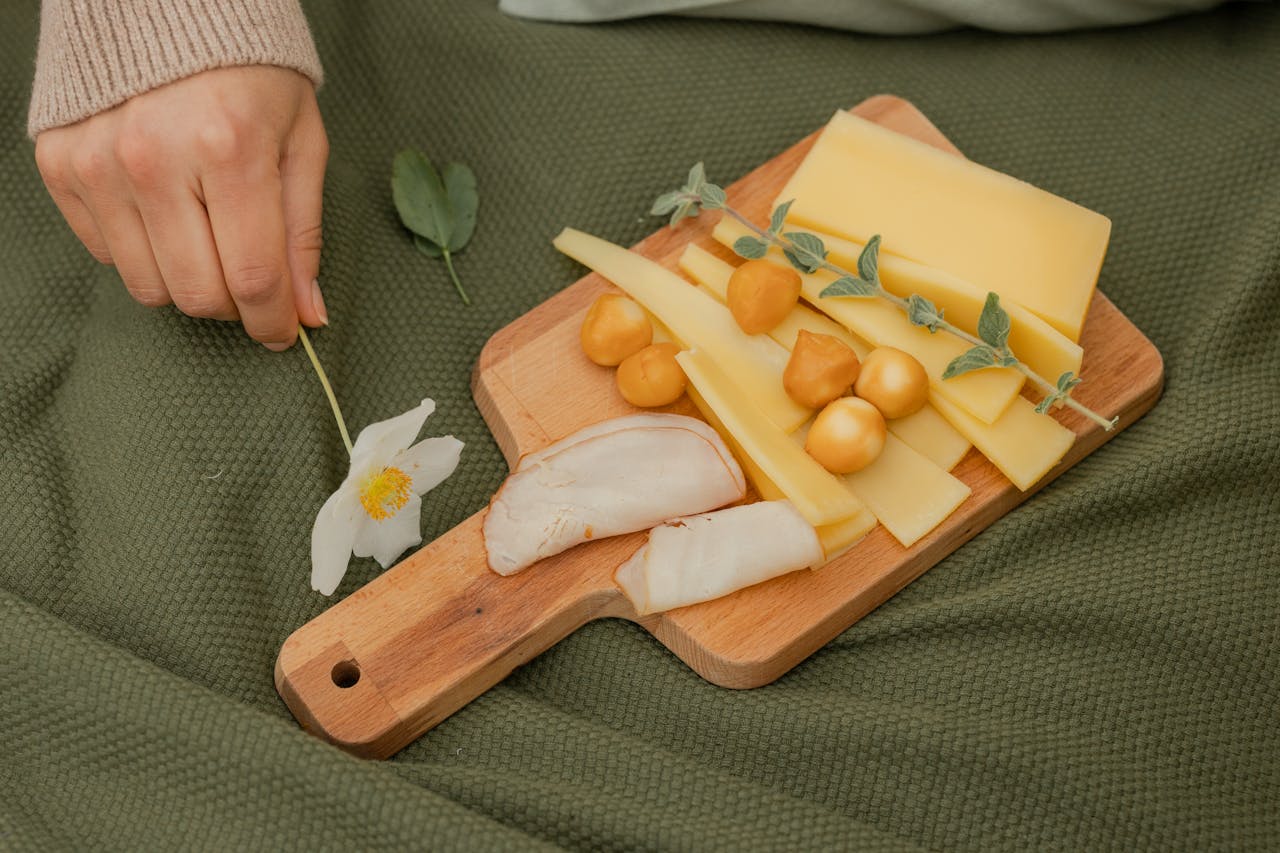 Cesta de pícnic con queso, baguette, uvas y vino sobre una manta en la hierba