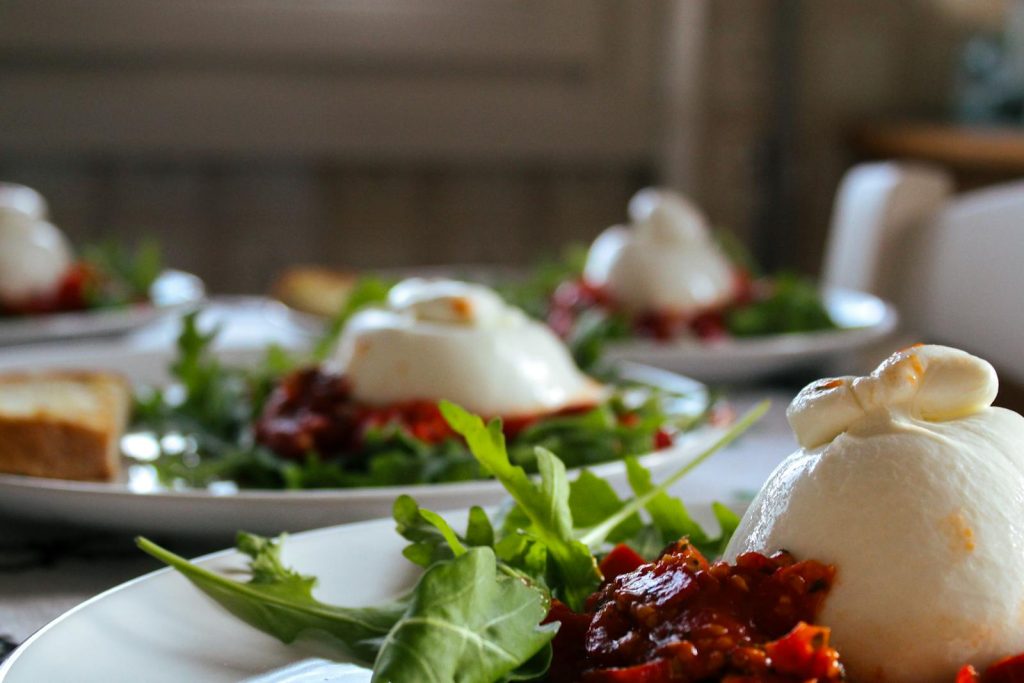 Verse Italiaanse burrata met romige stracciatella-vulling, geserveerd op rucola met tomaatrelish