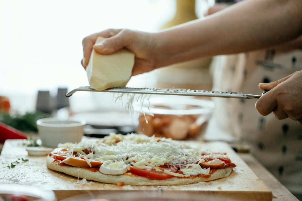 Verse Grana Padano raspen over een zelfgemaakte pizza