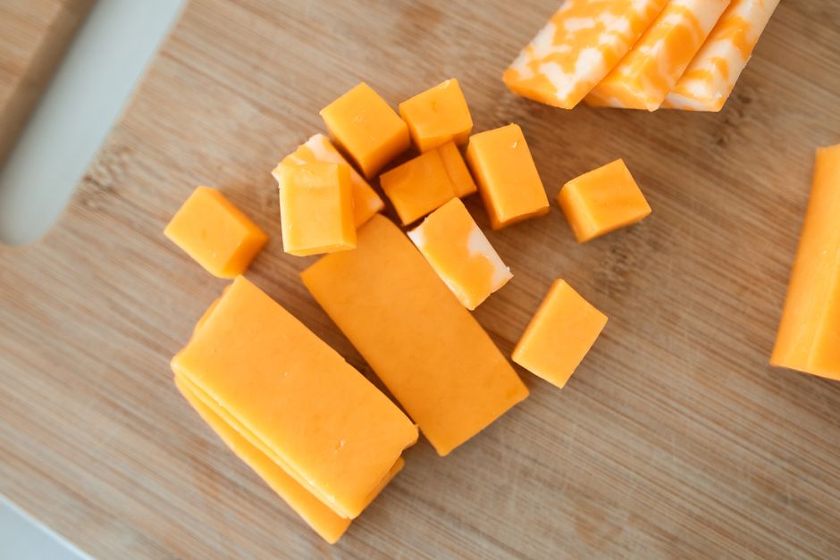 Blokjes en plakken cheddar op een houten plank met crackers, ideale opstelling voor een borrelplank met cheddar
