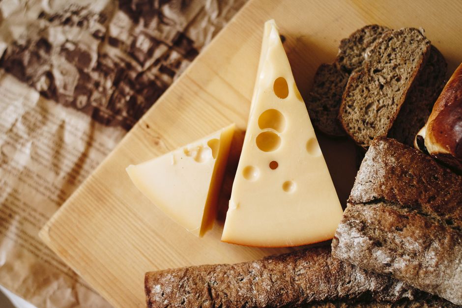 Plakken jonge gele graskaas met rustiek brood op een houten plank