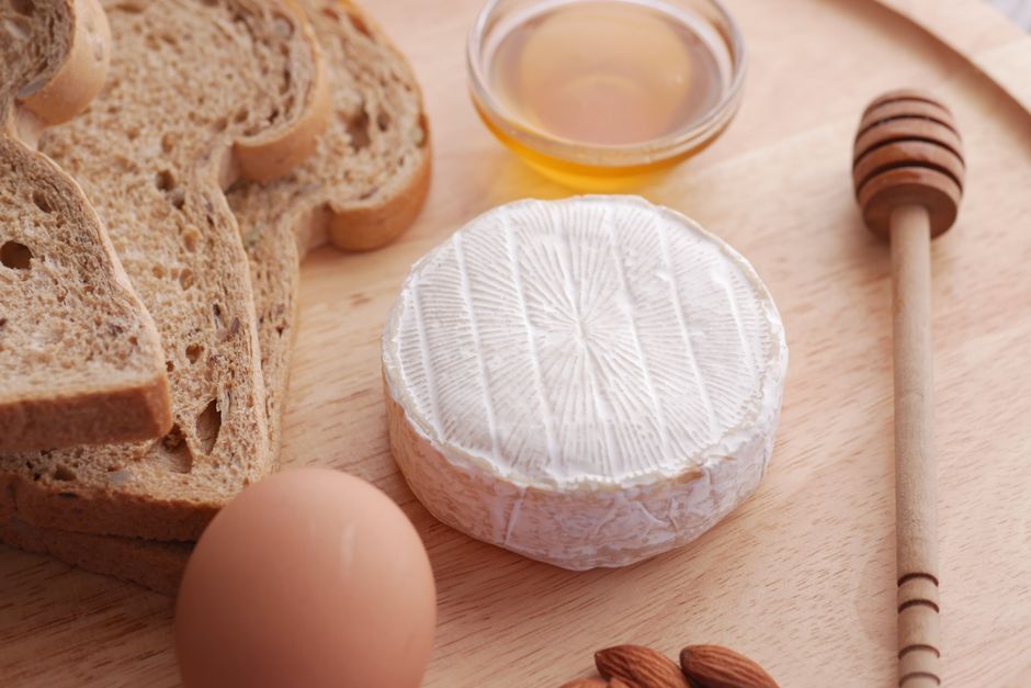 Zachte kaas met stokbrood, honing en amandelen op een houten plank