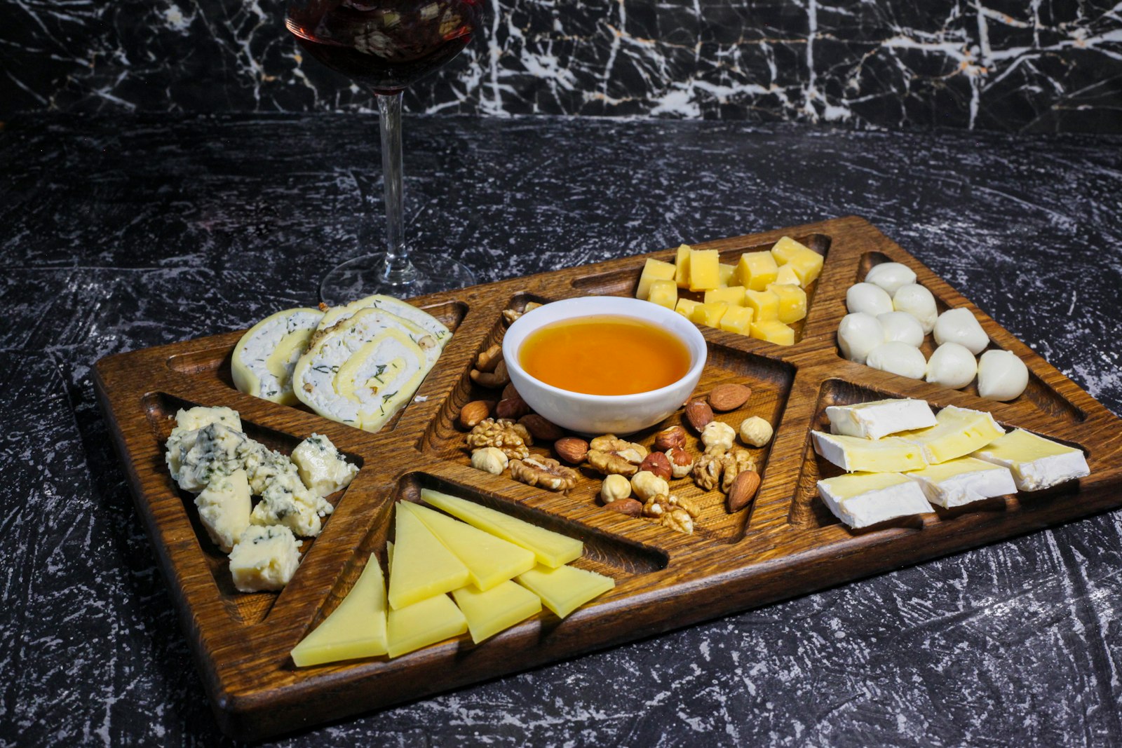 Kaasplank met stukjes bergkaas, noten, gedroogd fruit en honing klaar om te serveren